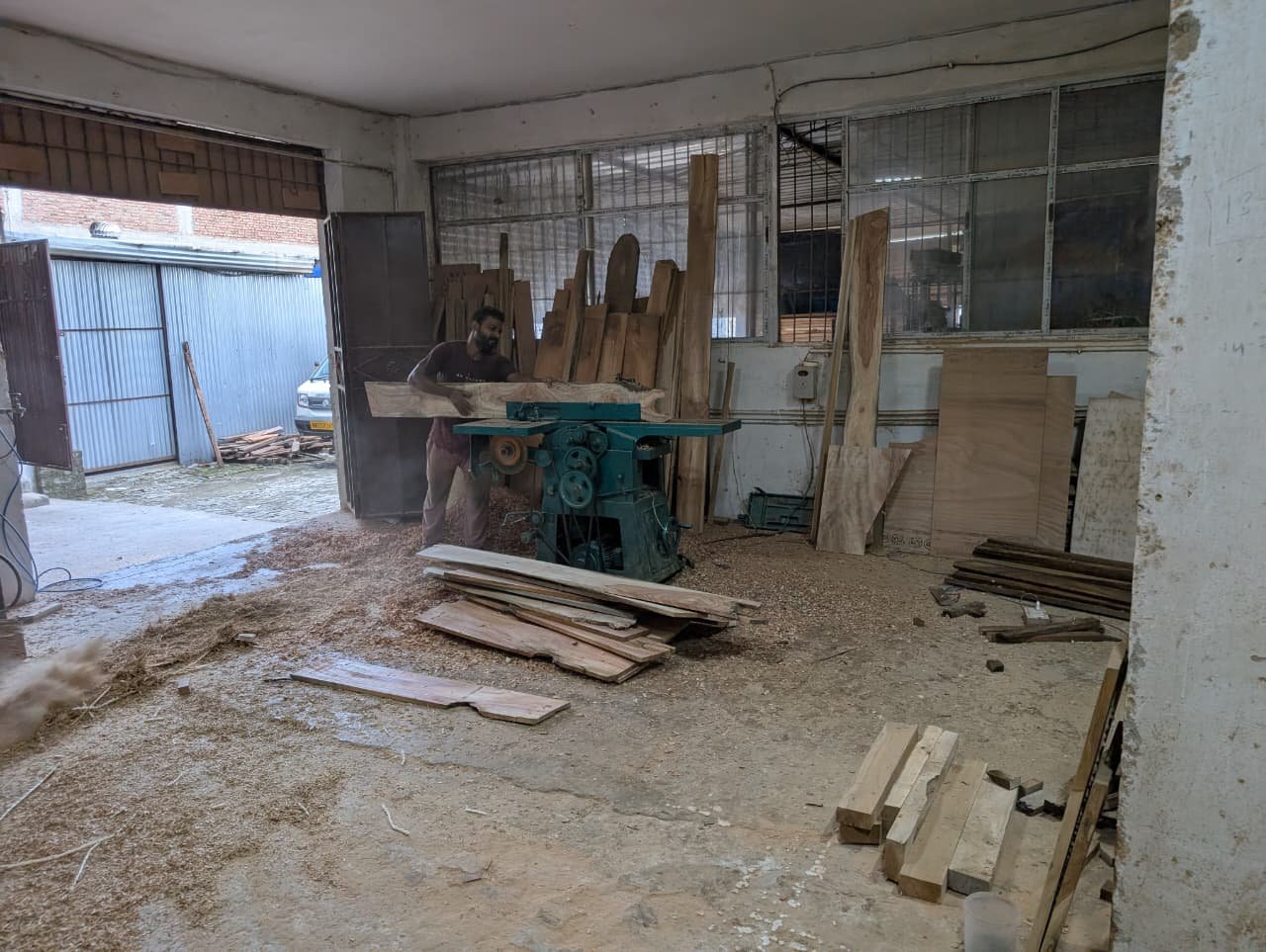 A carpenter feeding a board through the surface planer at the Kinwud works