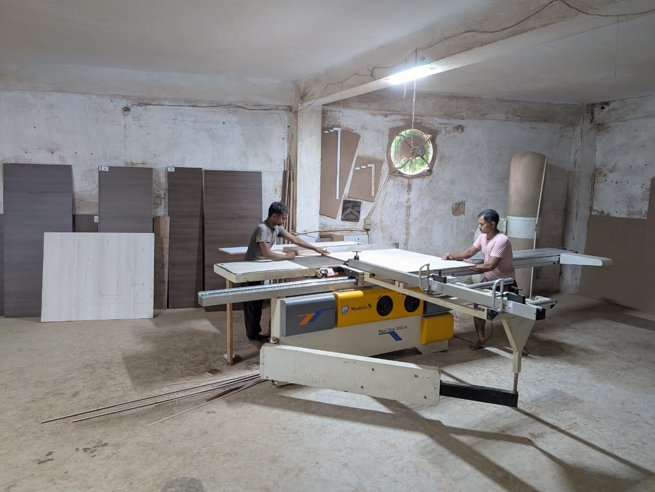 Two carpenters squaring a panel together on the sliding saw